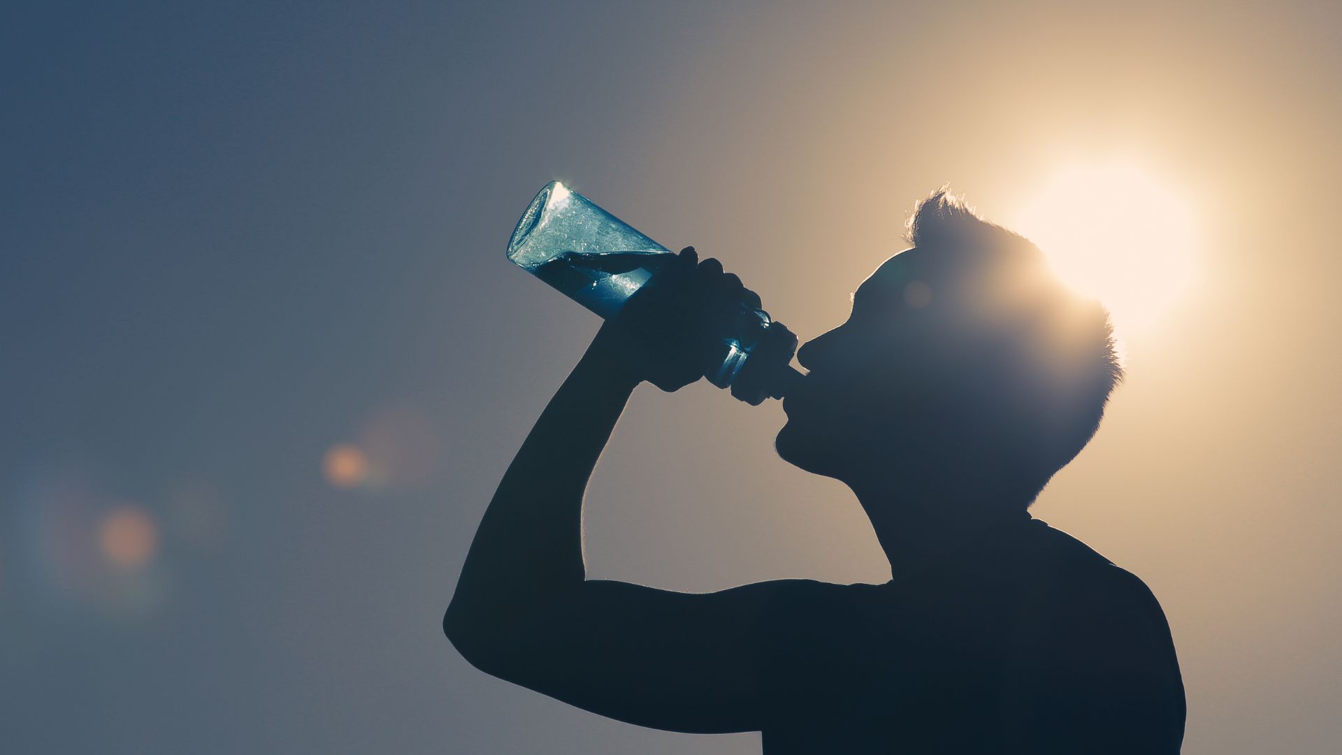 a man drinking a bottle of water in the sun